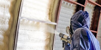 A spray foam insulation contractor applying spray foam in a steel building