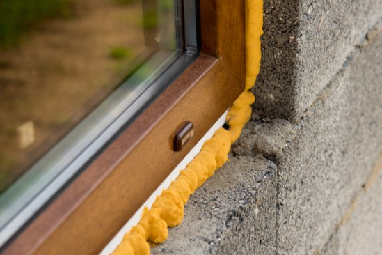 Window with spray foam insulation for improved air sealing