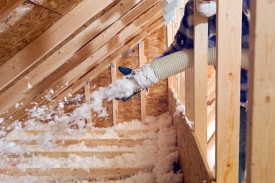 An insulation contractor installing blown-in blanket insulation in an attic