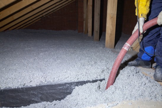 An insulation contractor installing blown-in cellulose insulation in a attic